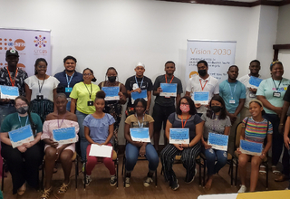Students seated and standing holding their certificates from capacity building session