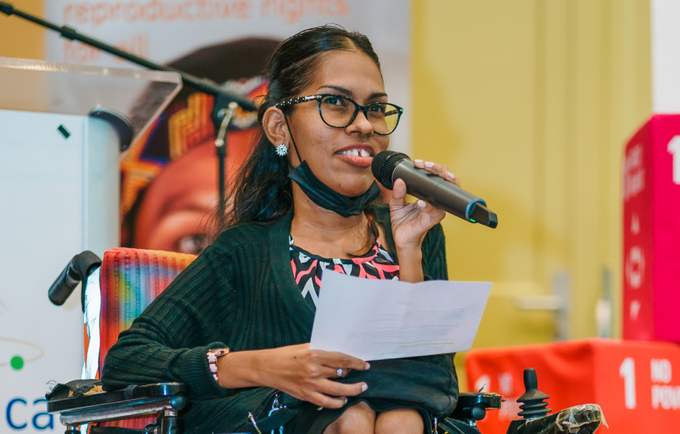 Woman in wheelchair holding microphone delivering speech
