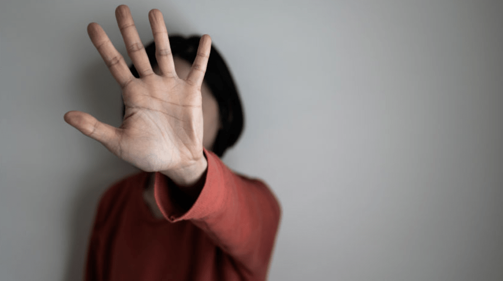 Girl shields face with palm (gender based violence)