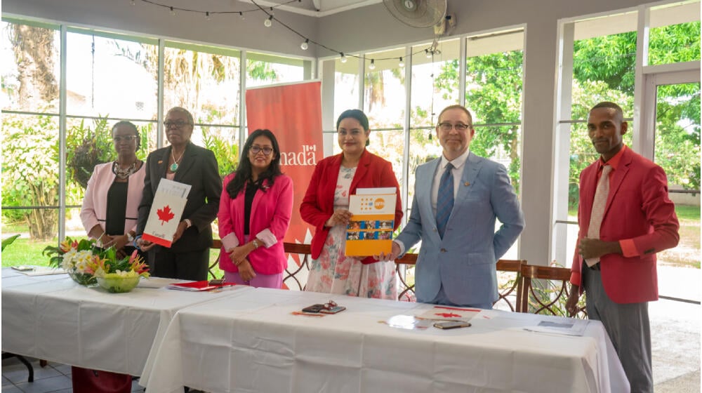 Officials stand behind table smiling for photo and holding signed document at launch