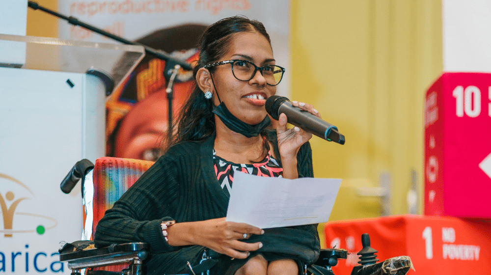 Woman in wheelchair holding microphone delivering speech