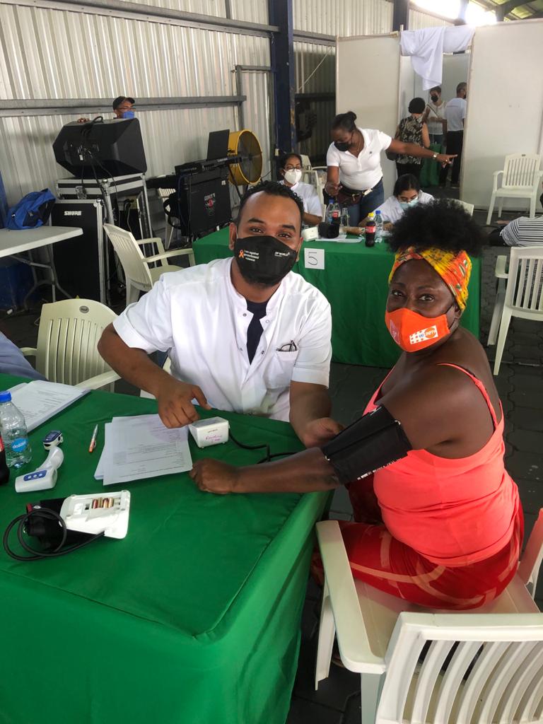 Photo shownig Hakiem volunteering while the Liaison Officer of the UNFPA Country Office in Suriname - Judith Brielle gets her COVID-19 vaccine.